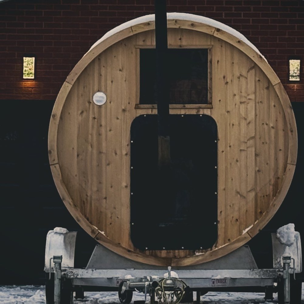 The standard wood-fired barrel sauna on its trailer, parked in a snowy driveway